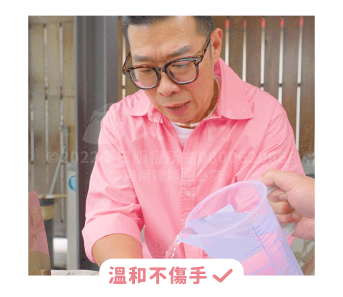 一名戴眼鏡、穿粉紅色襯衫的男子專注地看著前方。畫面右下方有一隻手正拿著帶有刻度的透明量杯，倒出清澈的液體。圖片下方有粉紅色字體寫著「溫和不傷手」並打紅色勾勾，強調洗衣機清洗劑的溫和特性。